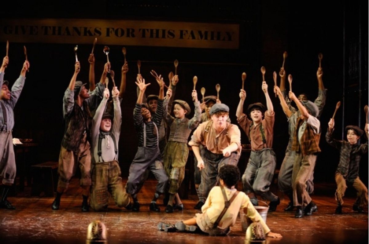 Yancey (standing, Chase Maxwell) encourages Twist (seated, Alaman Diadhiou) to ask for meat on his birthday while the children of the Parish House Orphanage at 